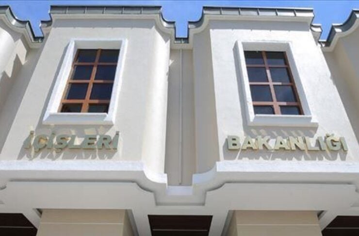 Facade of a government building labeled “İşleri Bakanlığı” with two guards in red and blue uniforms standing at the entrance.