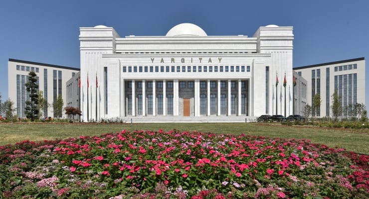 Front view of Yargıtay, a white domed courthouse with tall columns and flags, with a pink flower garden in the foreground.