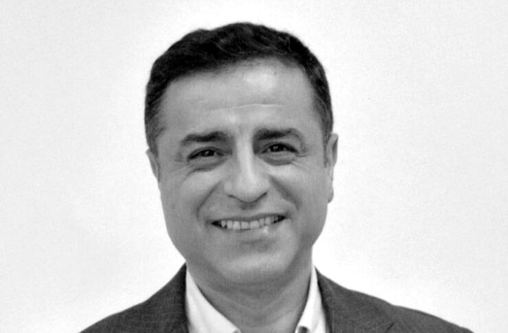 Professional headshot: smiling man in a suit and white shirt, facing the camera.