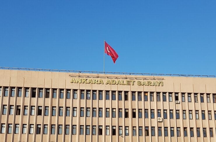 Facade of Ankara Courthouse (Ankara Adalet Sarayı) with a Turkish flag flying atop the building under a clear blue sky