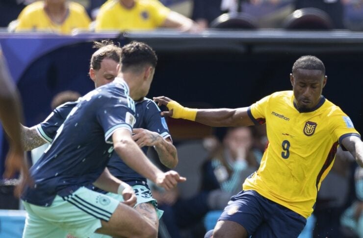 Soccer player in a yellow jersey (number 9) kicking the ball as blue-jersey opponents close in.
