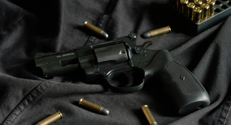 Black revolver lying on dark fabric with several bullets scattered around it, including a visible .38 Special marking on the barrel.