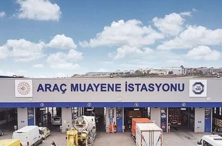 Front view of a vehicle inspection station in Turkey, with several trucks and vans in service bays under a sign reading 'ARAÇ MUAYENE İSTASYONU'.