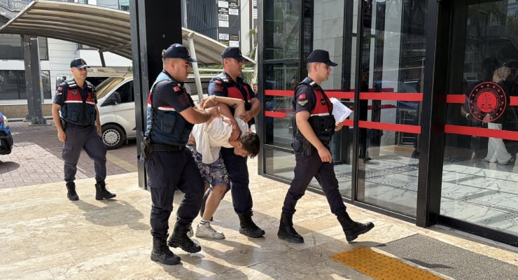 Police officers restraining a man outside a glass-front building.