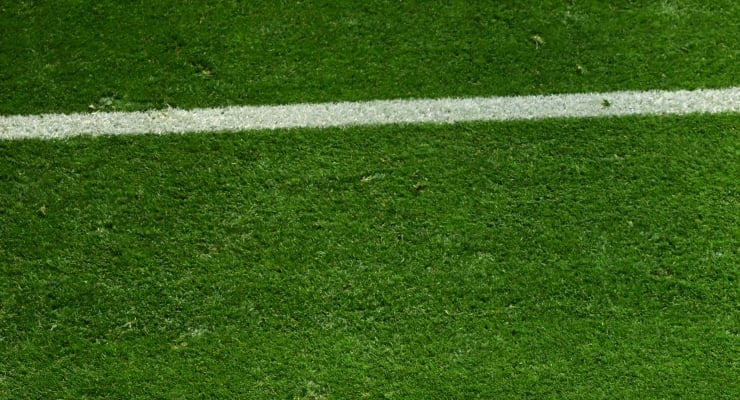 Close-up of green turf with a white painted line, as seen on a sports field boundary.