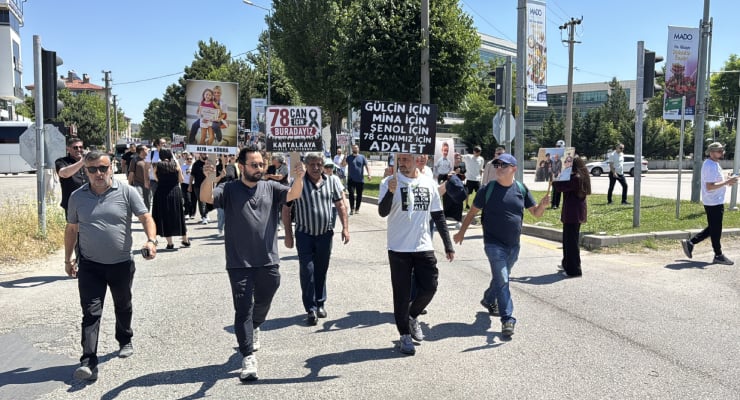 Group of protesters walking down a sunny city street, holding placards with Turkish slogans and photos, including 'Adalet' (justice).