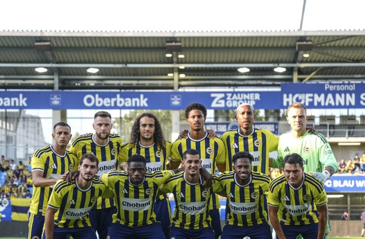 Soccer team in yellow-and-blue striped jerseys poses for a group photo on the pitch, with a green-clad goalkeeper at the back right.
