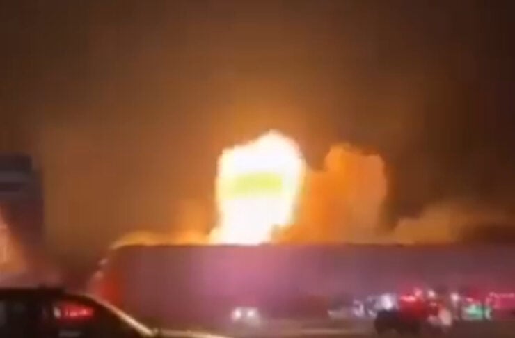 Nighttime highway incident with a large fire and emergency vehicles nearby.