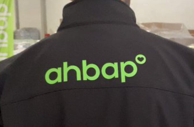 Back view of a black jacket with a bright green 'ahbap°' logo on the upper back area.