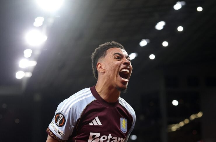 Aston Villa player in maroon kit celebrates with fists clenched and mouth open in a stadium celebration moment.