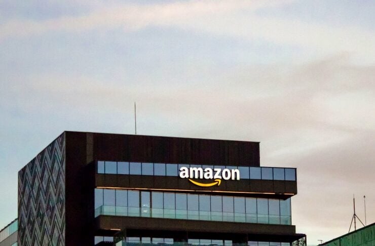 Amazon-branded modern glass office building with logo on top floor, blue sky in background