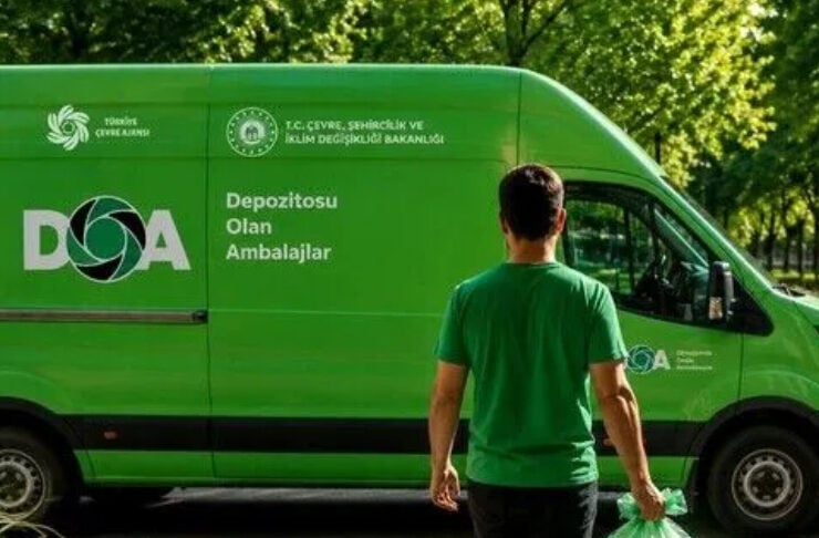 A man in a green T-shirt carrying a large transparent bag filled with plastic bottles beside a bright green recycling van with Turkish logos.