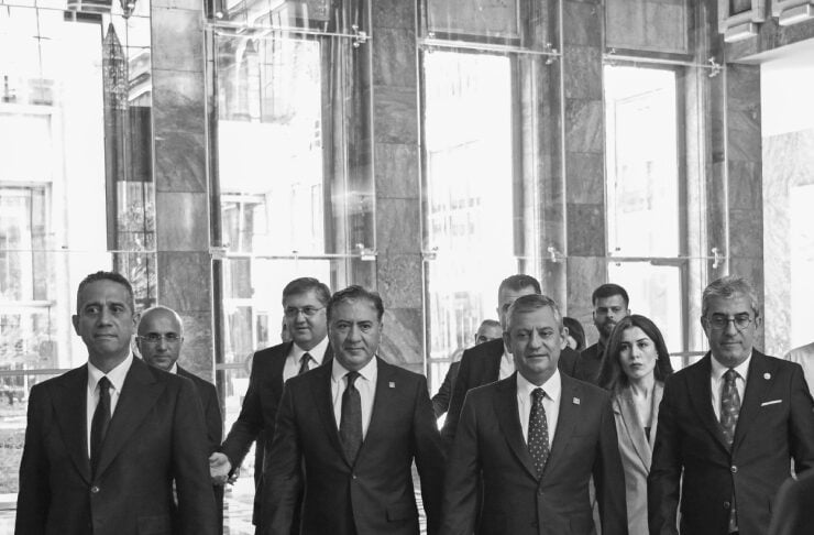 Group of suited professionals walking through a glass-front lobby toward the camera in a modern office building.
