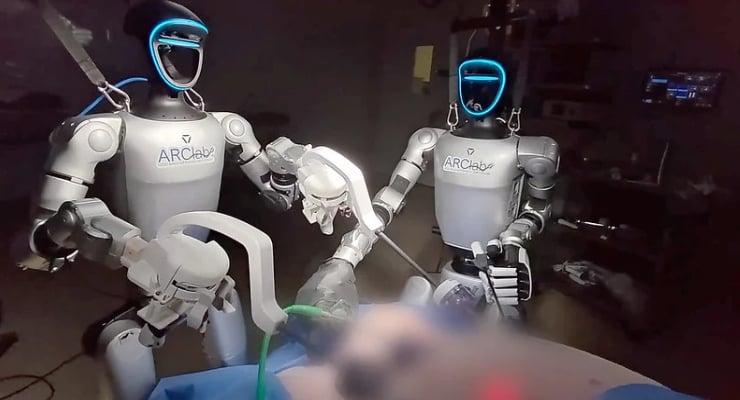 Two ARCLab surgical robots with blue-lit helmets assist a patient on an operating table, using robotic arms for a procedure in a dim lab setting.