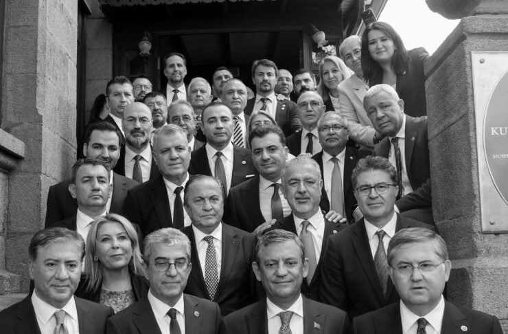 Group of people in suits posing on stone stairs for a formal group portrait outside a building.