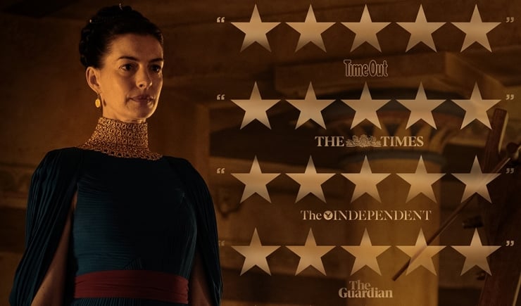Portrait of a woman in a dark teal historical dress with a red sash, standing left, and a backdrop of star ratings and newspaper logos on the right.