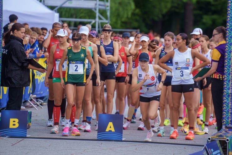 Group of female runners at the starting line of a race, bib numbers visible, with A and B start markers nearby and officials on the sides.