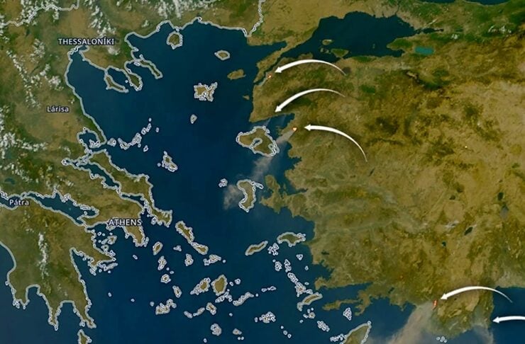 Satellite map of Greece showing the Aegean Sea with white arrows indicating wind or plume movement from land toward the sea.