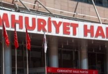 Front of CHP party building with a large red sign reading 'CUMHURİYET HALK PARTİSİ', a red CHP logo panel, and Turkish flags outside.