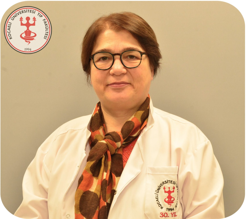 Portrait of a woman in a white lab coat and patterned scarf, wearing round glasses, standing against a beige background with a university medical faculty emblem on the coat pocket.