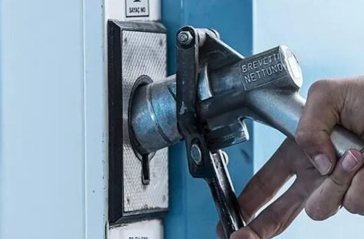 Close-up of a hand holding a fuel nozzle inserted into a blue gas pump.