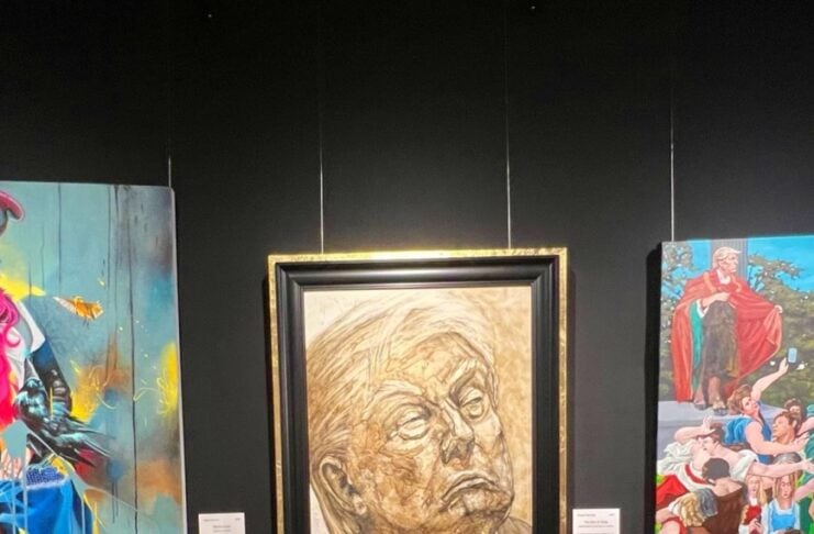 Center framed charcoal portrait of a stern, balding man with closed eyes, displayed on a dark gallery wall between two colorful paintings.