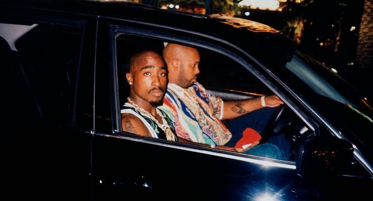 Two men in a dark car at night; one looks toward the camera while the other drives.