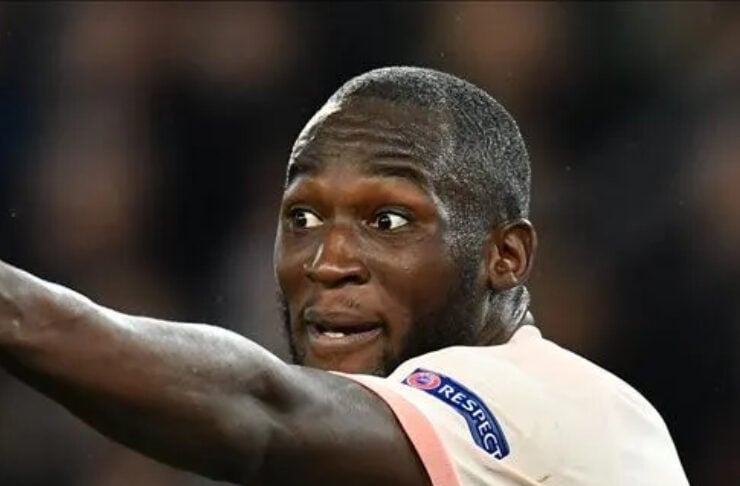 Soccer player in a cream jersey with UEFA patch on the sleeve, pointing to the left with a surprised expression.
